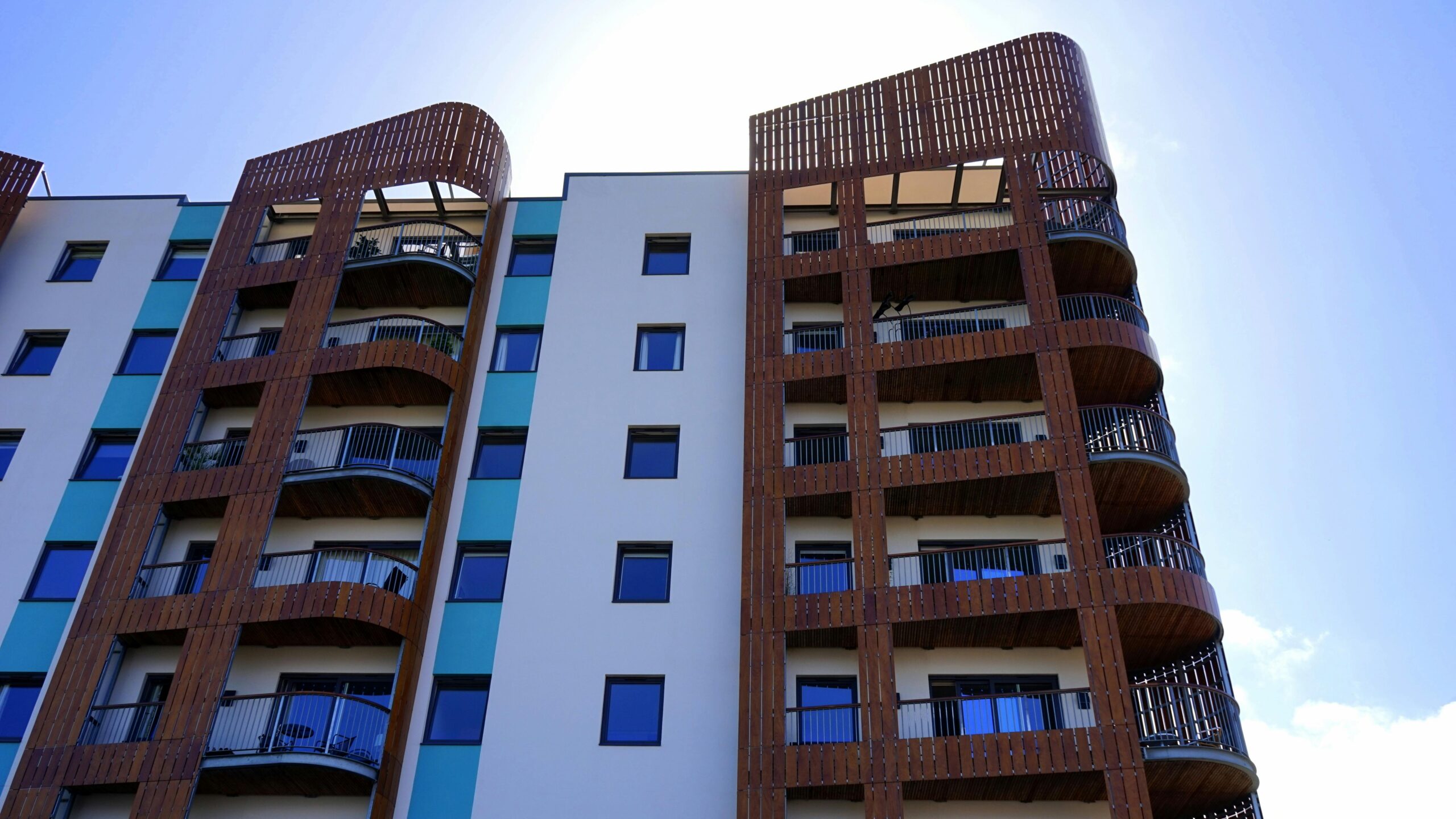 Explore the contemporary design and architecture of urban apartments with wooden accents and blue sky backdrop.